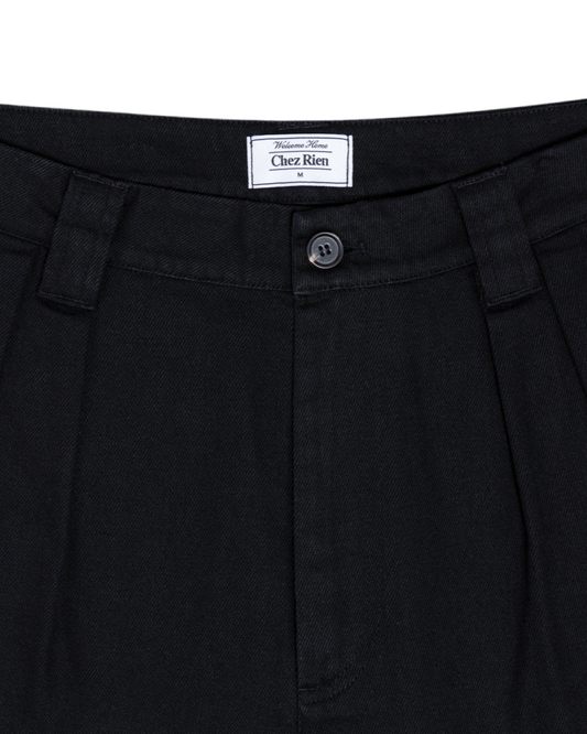 Close-up of black shorts with a ‘Chez Rien’ brand label on a white background