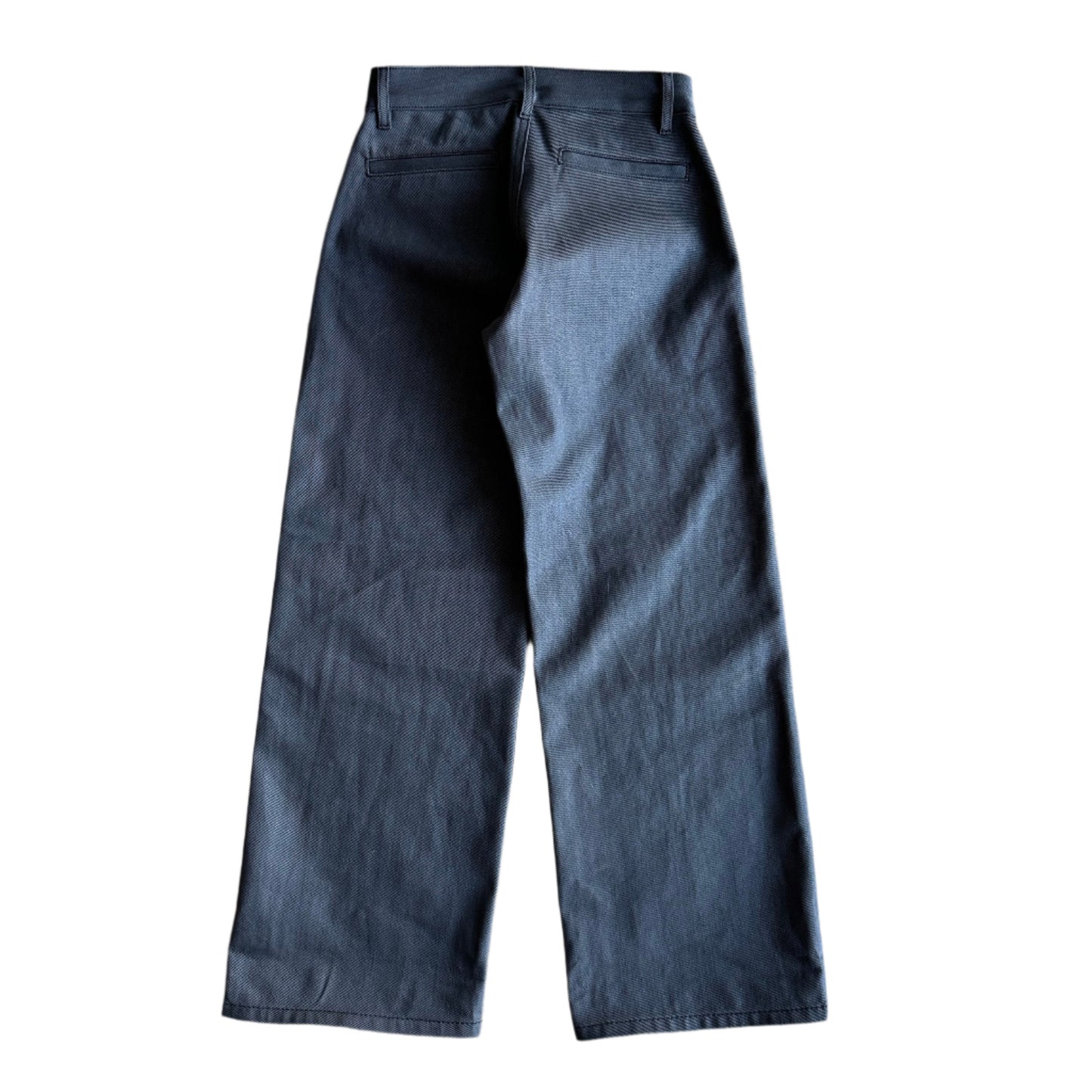 Back of The Hidden Rivet Grounded Charcoal Selvedge Denim on a pebbled brown background