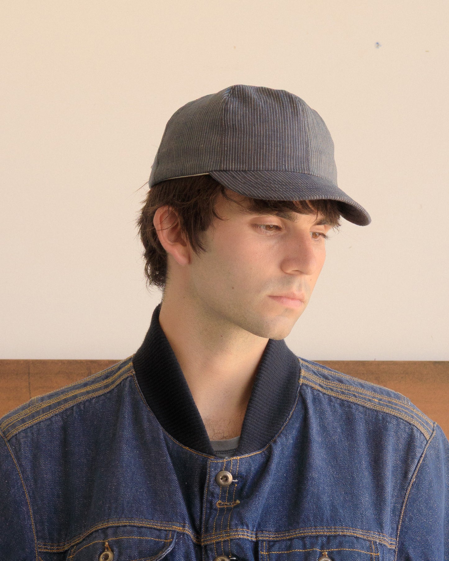 Man wearing a Blue Thin Stripe Warden Cap and denim jacket against a plain background