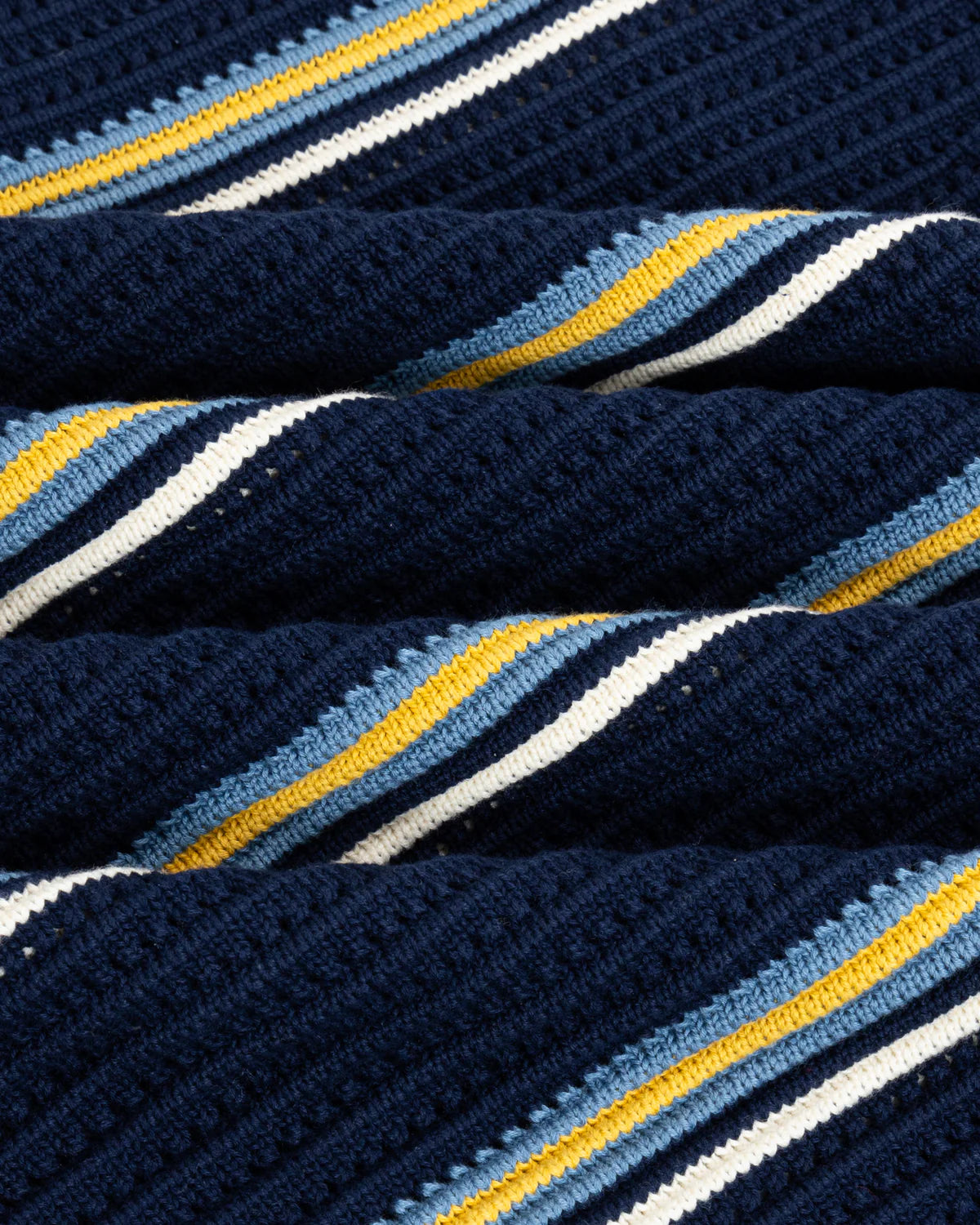 Close-up of a Chez Rien’s Striped Knit Polo fabric with blue, yellow, and white stripes.