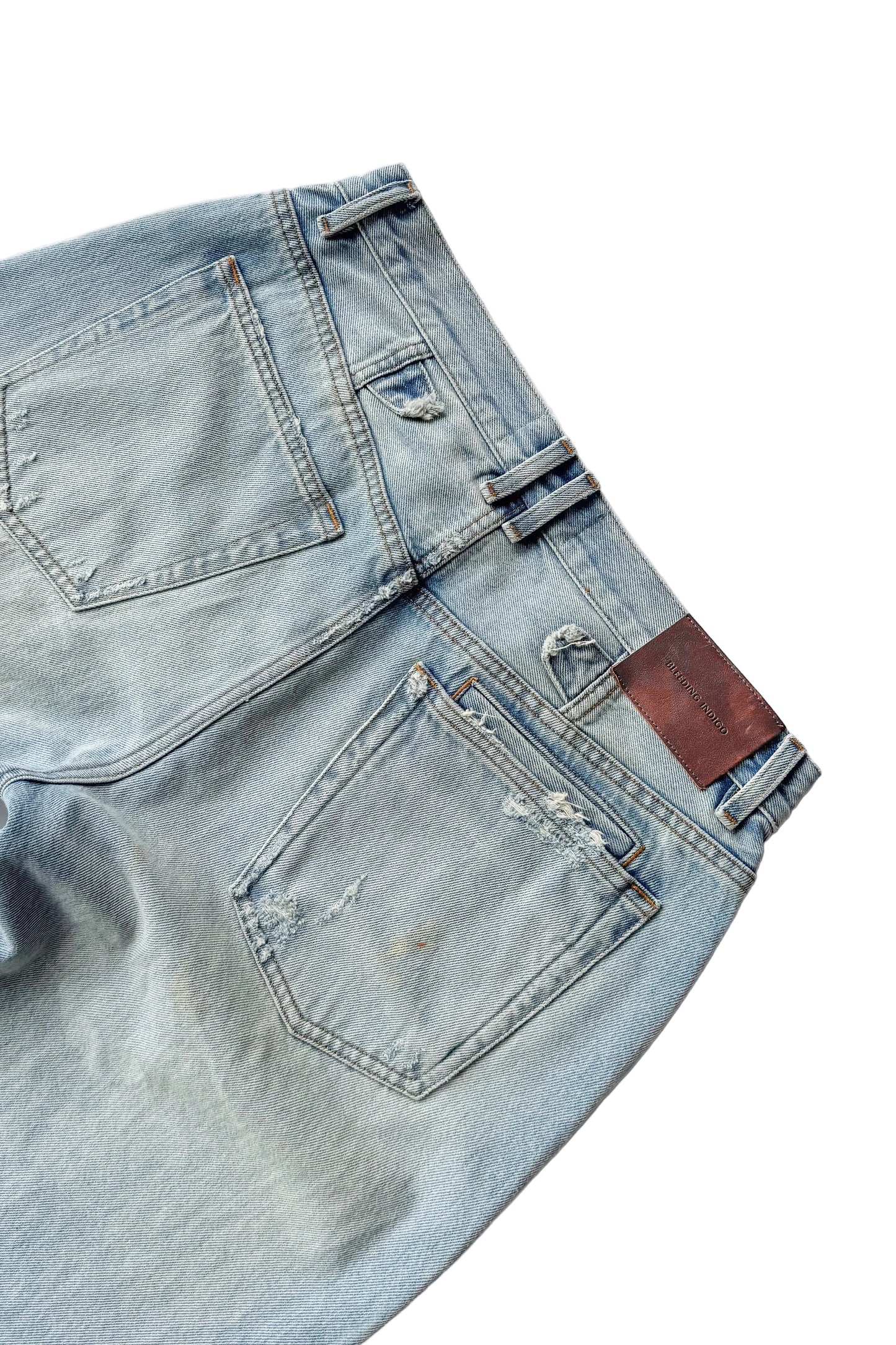 Close-up of a pair of light blue jeans with a patch on a white background