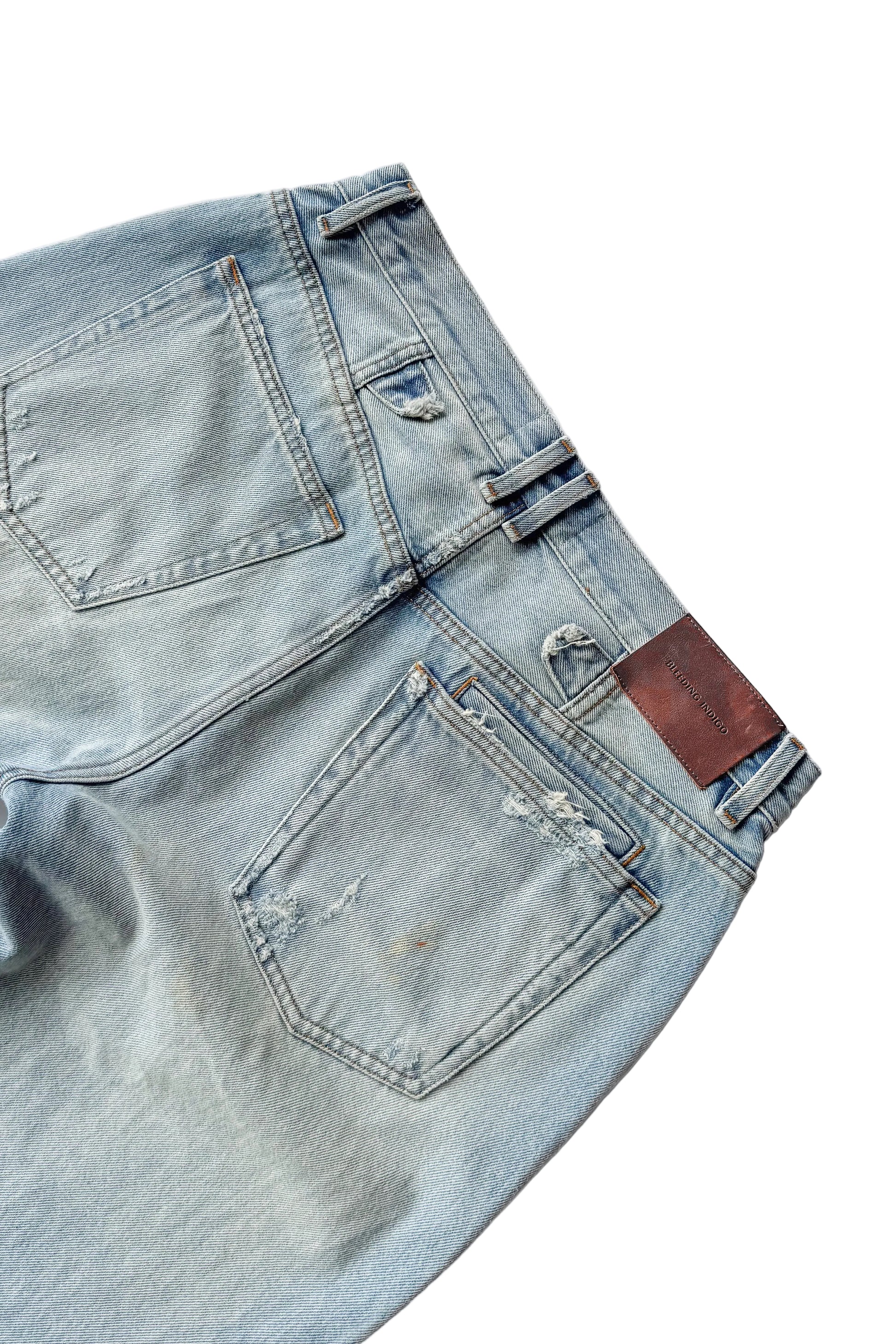 Close-up of a pair of light blue jeans with a patch on a white background